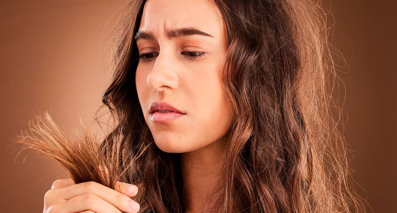 mulher olhando para as pontas do cabelo danificado